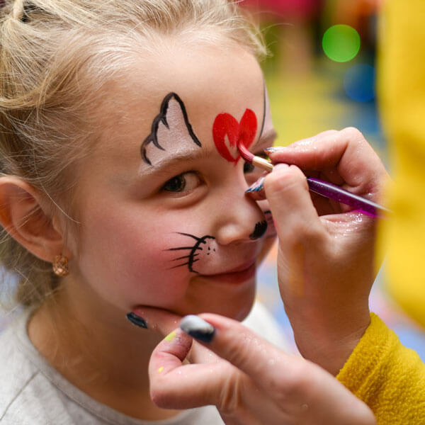 face painter in process of painting a heart on a child's forehead